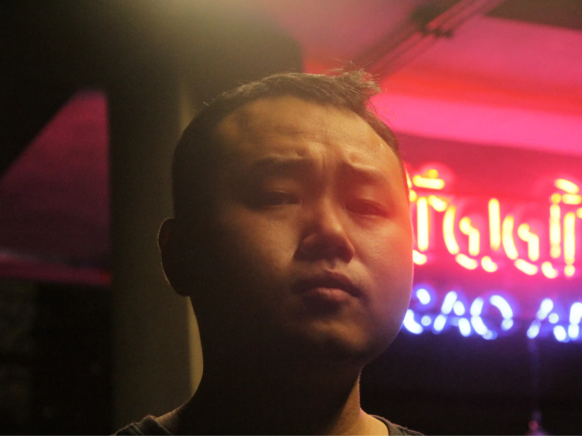 Mlad moški, fotografiran pred neonskim napisom